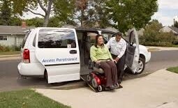 Paratransit bus with patient being helped off in a wheelchair