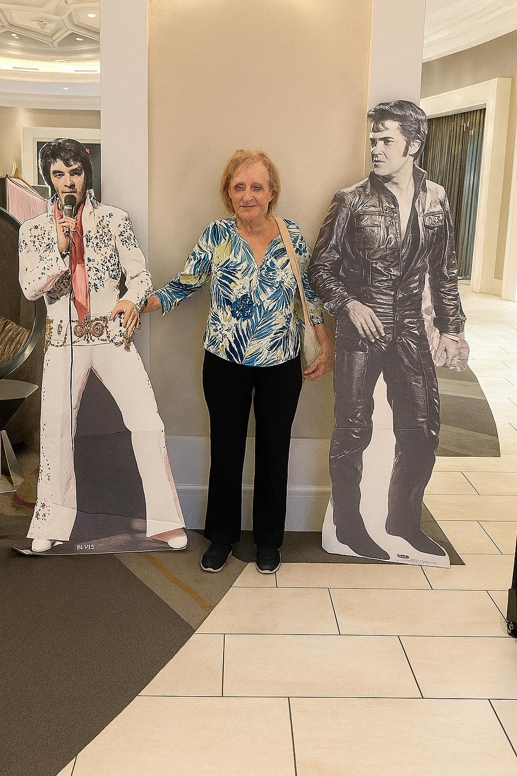Sylvia standing between two life sized cutouts of Elvis during checkin at the Graceland Guest House