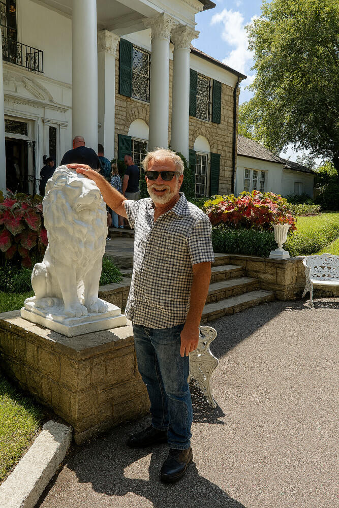 Mt son standing by one of the  lion statues at the front door of Graceland