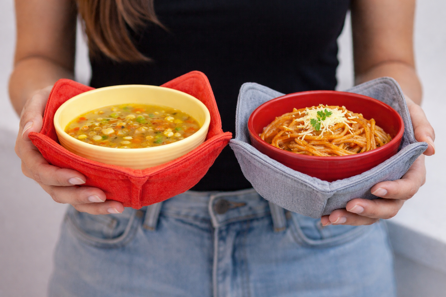Person holding two microwave bowl cozies—one red with a yellow bowl and one gray with a red bowl—demonstrating color contrast for safer handling of hot food